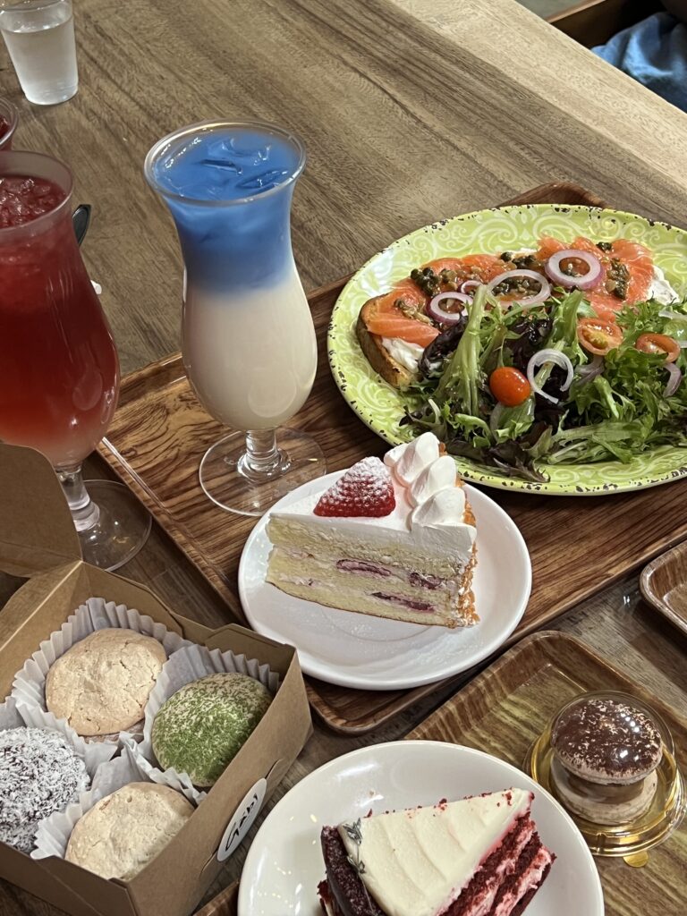Wooden table full of decorative desserts and colorful drinks on trays.
