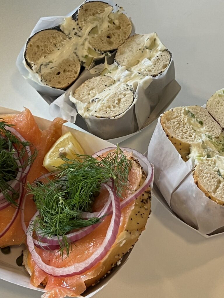 Salmon lox bagel next to cream cheese bagel split open.