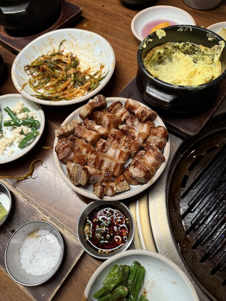 plate of grilled pork belly with surrounding side dishes