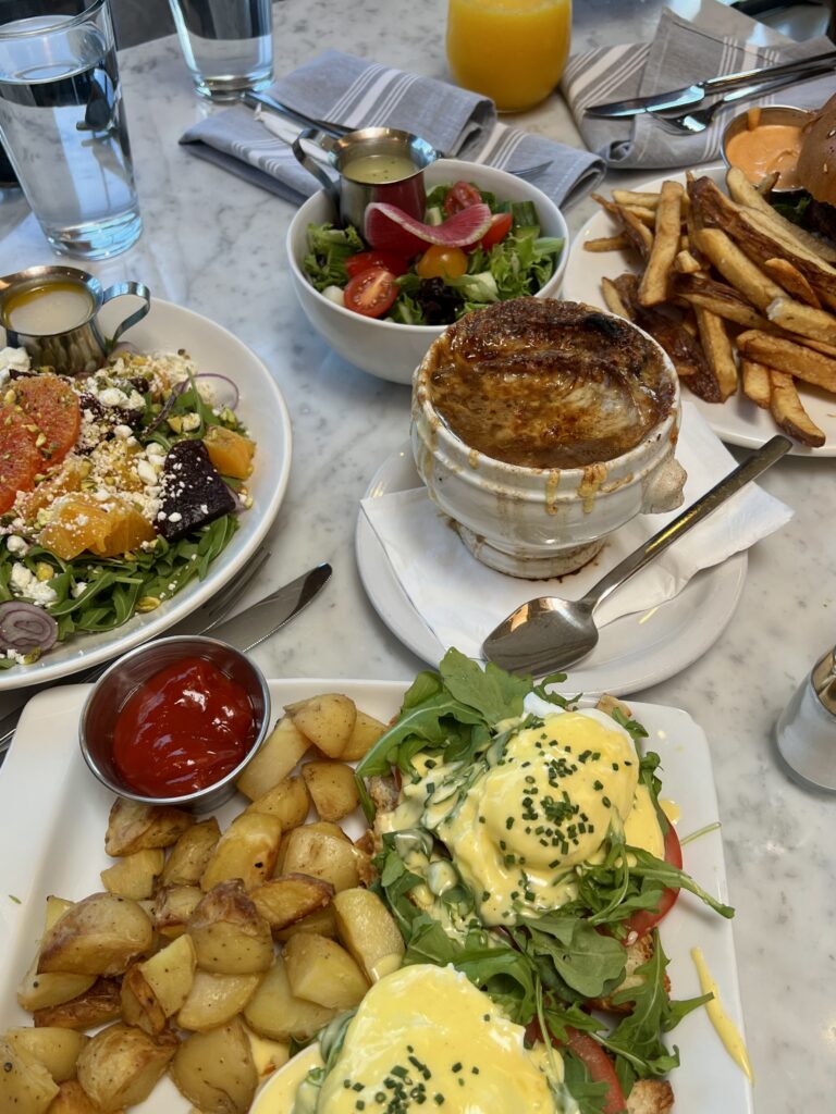 spread of different brunch foods--eggs benedict, french onion soup, salad