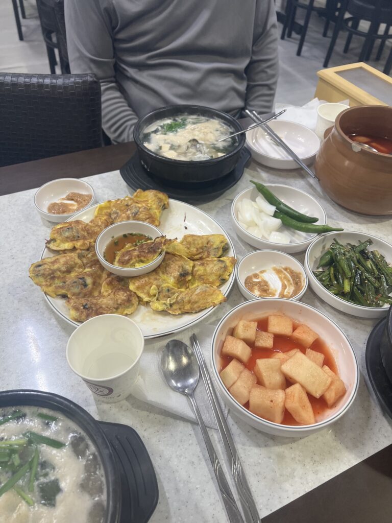 oyster pancake next to korean side dishes on table